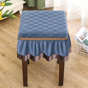 Detailed view of square velvet stool cover with elegant gold trim and ruffled edge.