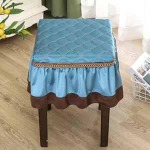 Blue quilted square stool cover with brown ruffle trim for home vanity and piano bench use.