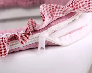 Detailed view of a pink and red checkered fabric toilet seat cover with cute ruffles and zipper.