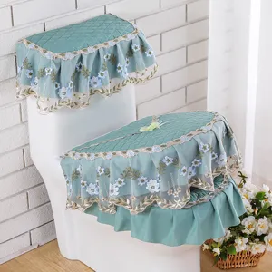 Vista detallada de un juego de fundas de inodoro verde acolchado con bordado floral azul.