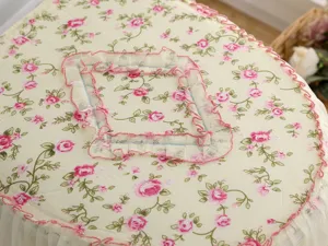 Gedetailleerde close-up van de stoffen toiletdekselhoes met bloemenprint en kanten volant.