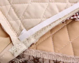 Close-up detail of quilted toilet seat cover showing neat stitching, elastic band, and lace.