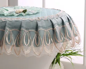 Close-up detail of fabric toilet seat cover with exquisite lace embroidery and floral accent.
