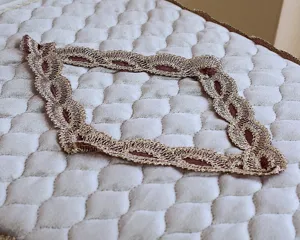 Detalle de ribete de encaje dorado exquisito para funda de asiento de inodoro moderna de terciopelo.