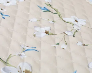 Close-up detail of quilted fabric with pastoral floral pattern, showing texture and stitching.