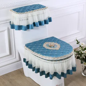 Blue quilted fabric toilet seat cover set with elegant white lace ruffles and floral embroidery.