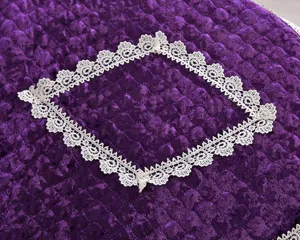 Velvet toilet seat cover detail, purple fabric with white lace trim, soft home textile texture.