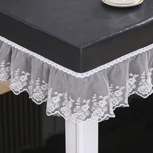 Close-up detail of black PU leather table cover with elegant white lace ruffle edges.