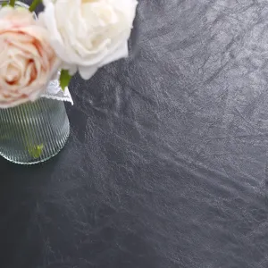 Dark grey PU leather tablecloth detail, textured surface and artificial rose decor.