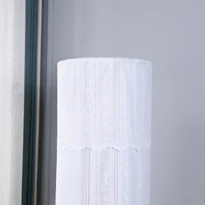 Dettaglio del copricondizionatore cilindrico in pizzo bianco con ricamo floreale.