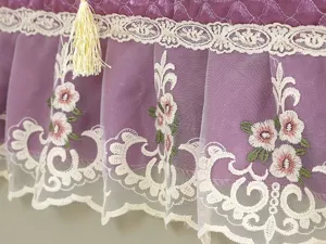 Lila gesteppte Kühlschrank-Staubschutz-Detail mit weißer Spitze, Blumenstickerei und Quaste.