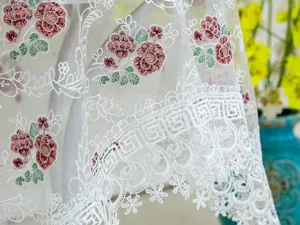 Detalle exquisito de un mantel de encaje blanco con delicados patrones florales y bordes.