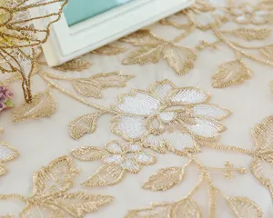 Detailed view of elegant gold embroidered lace tablecloth featuring exquisite floral and leaf patterns.