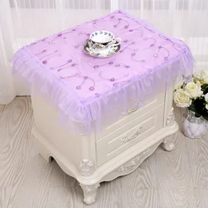 Detalle del mantel de encaje morado para mesita de noche con bordados florales y volantes