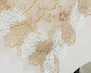 Detailed shot of delicate gold and white floral lace embroidery table runner and cover.