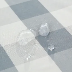 Gros plan detaille d'un tissu carre gris et blanc impermeable montrant son effet deperlant.