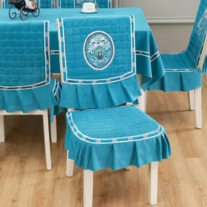 Détail d'une housse de chaise bleue matelassée et d'une belle nappe avec broderie florale délicate.