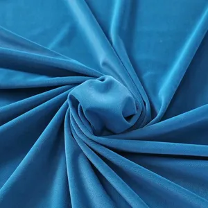 Gros plan détaillé de tissu en velours bleu doux avec texture lisse et drapés élégants.