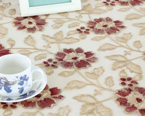 Exquisite embroidered tablecloth detail featuring elegant red floral motifs on sheer mesh fabric.