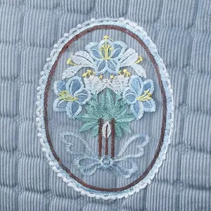 Vue détaillée d'un coussin de chaise matelassé avec broderie florale bleue et nœud.