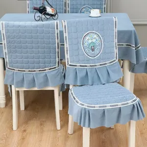 Détail de housse de chaise et nappe matelassées bleues, tissu doux avec broderie florale.