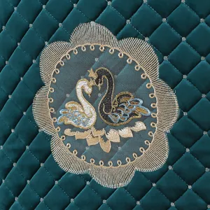 Detailed close-up of dark green Italian velvet table cloth with elegant swan embroidery.