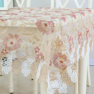 Detailed shot of exquisite sheer lace tablecloth with pink floral embroidery and white lace trim.