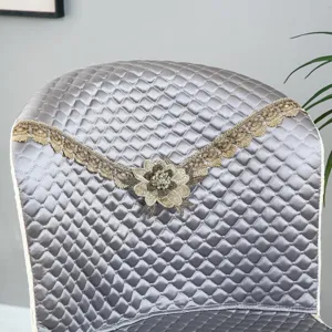 Grey quilted chair cover detail featuring elegant gold lace and central floral embroidery.