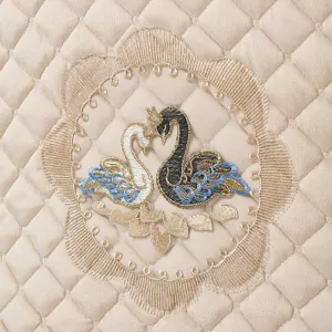 Close-up of beige quilted Italian velvet fabric featuring exquisite swan embroidery and lace trim.