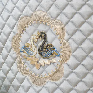 Italian velvet chair cushion detail featuring elegant swan embroidery and quilted pattern.