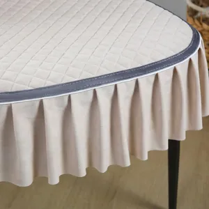 Exquisite quilted beige dining chair cover featuring a stylish ruffled skirt and sleek grey trim.