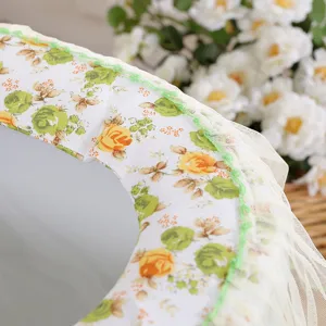 Gedetailleerde close-up van zachte bloemige toiletzittinghoes met elegante groene kanten rand.
