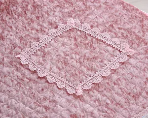 Pink golden velvet toilet seat cover fabric close-up shot with delicate lace trim.
