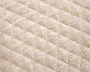Close-up detail of golden quilted fabric with delicate floral pattern, soft and elegant.