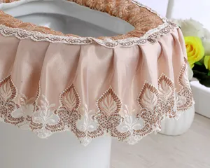 Detail shot of gold velvet toilet seat cover with elegant lace ruffle and embroidery.
