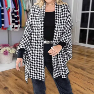 Detailed view of women's black and white houndstooth knit cape shawl, split design.