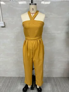Detail shot of yellow linen blend halter neck jumpsuit, featuring stylish cross straps and loose fit.