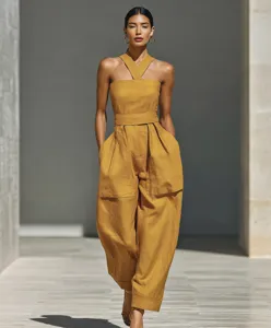 Detail view of the elegant yellow halter neck linen blend jumpsuit showing wide leg.