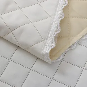 Quilted dust cover fabric detail showing elegant diamond stitching and delicate white lace trim.