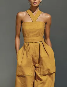 Close-up view of the stylish mustard yellow halter jumpsuit with cross strap and pockets.