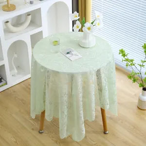 Vue détaillée de l'élégante nappe en dentelle florale vert menthe sur une table en bois