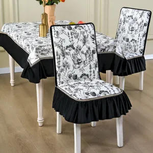 Housse de chaise de salle à manger florale noire et blanche avec jupe à volants et bordure dorée.