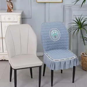 Detail view of the blue quilted dining chair cover with floral embroidery and delicate lace trim.