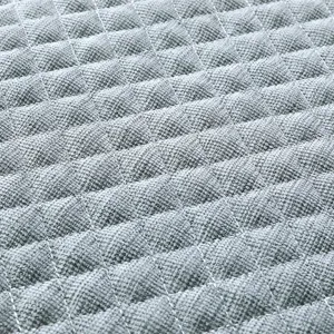 Primo piano della texture del tessuto trapuntato grigio a rombi, cuciture fini e materiale morbido.