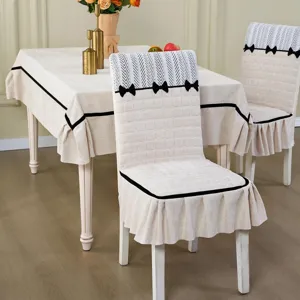 Dining table cloth and chair cover detail scene setup, beige fabric with black bow trim design.