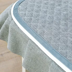 Vista dettagliata della tovaglia trapuntata grigia con elegante bordo blu e bianco.