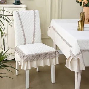 Detailed view of elegant quilted chair cover and tablecloth with delicate lace trim for home decor.
