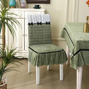 Detail of green quilted dining chair cover with black bow and edge trim, home decor.