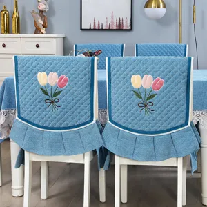 Dettaglio della fodera per sedia da pranzo blu trapuntata con ricamo di tulipani e volant.