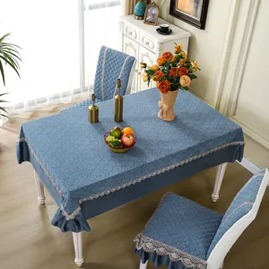 Detailed view of blue quilted dining tablecloth and matching chair covers with elegant lace trim.